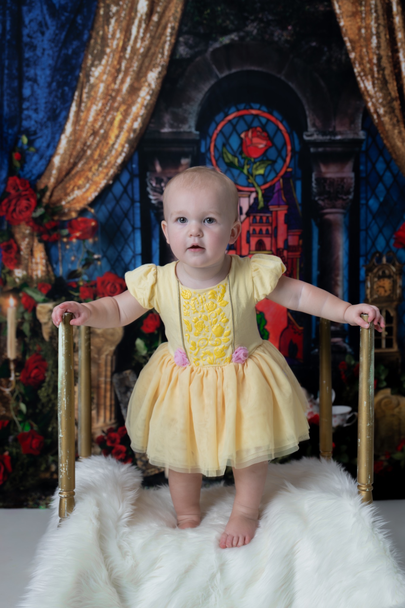 Child standing in a yellow dress in front of a castle-themed backdrop