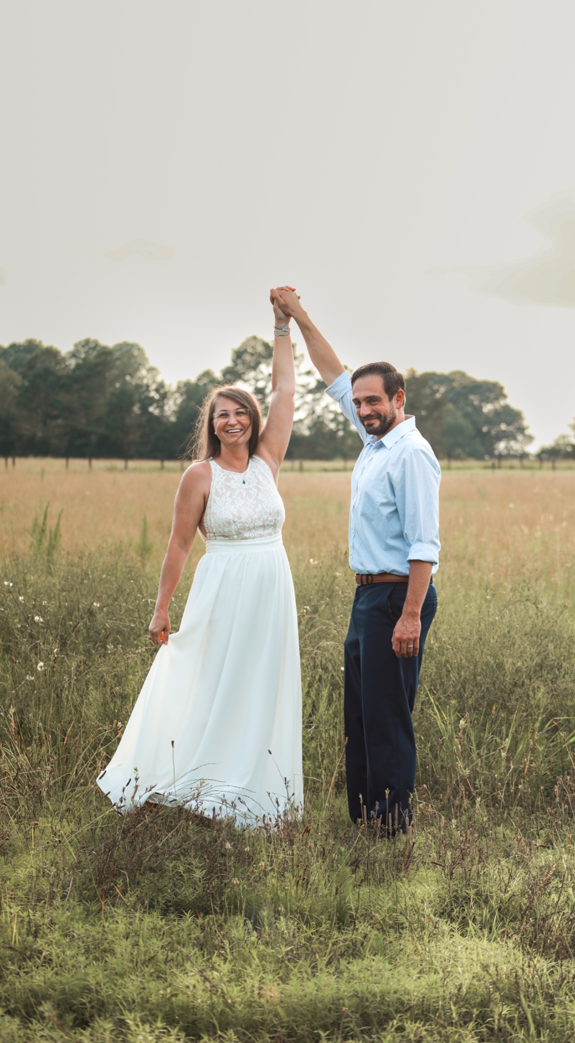 Couple holding hands during a twirl in a meadow