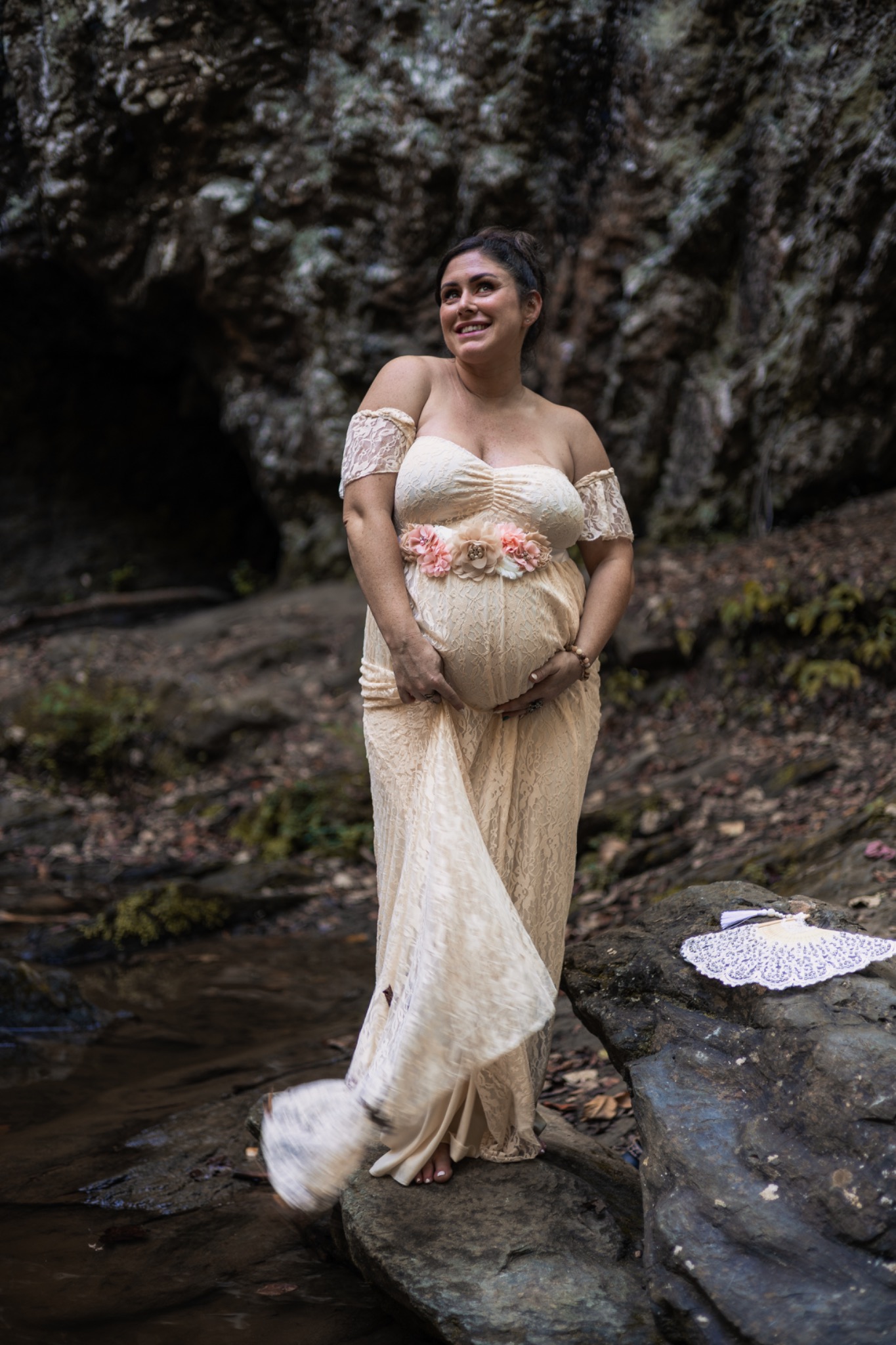 Maternity portrait in an ivory gown beside a rocky creek