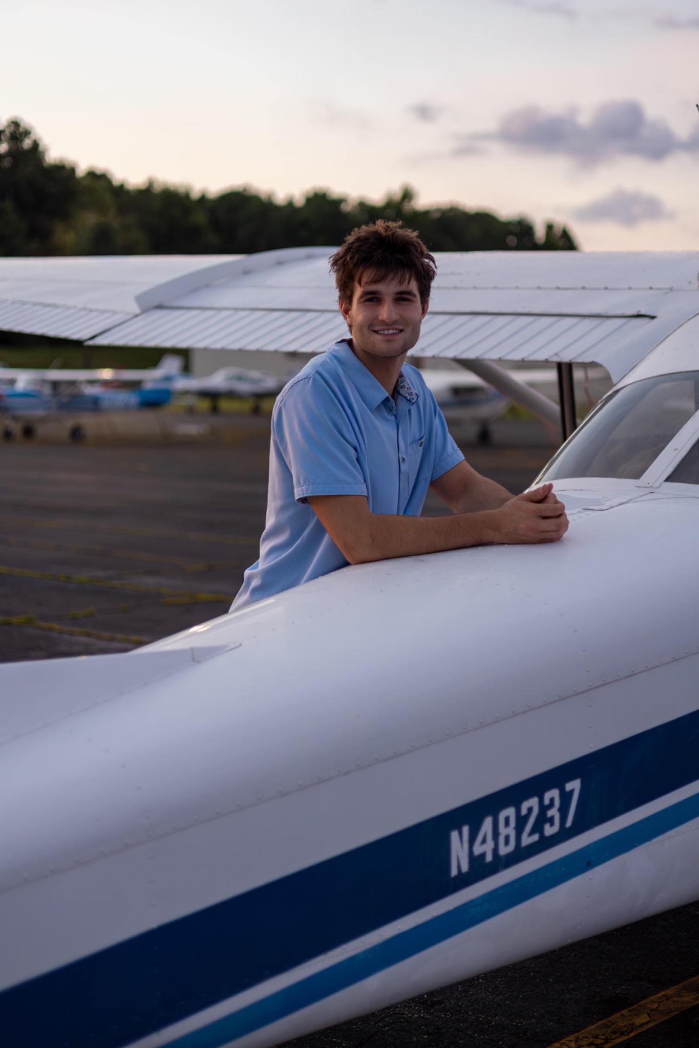Senior leaning on a small airplane at the airfield