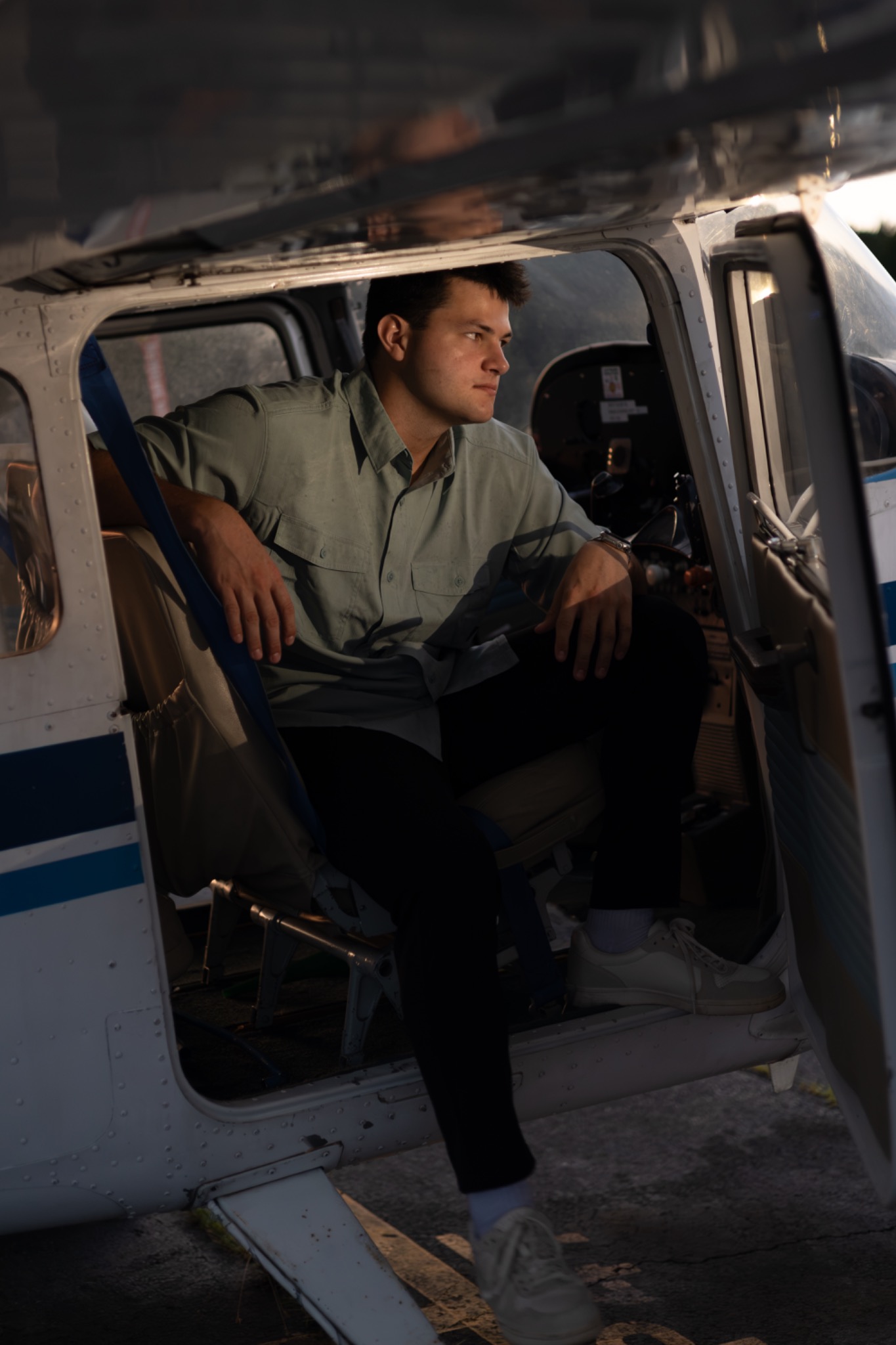Senior seated in the open doorway of a small airplane cockpit